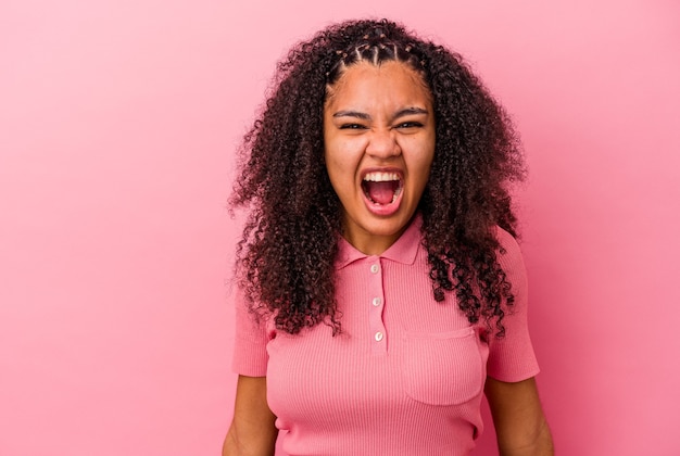 Giovane donna afroamericana isolata su sfondo rosa che grida molto arrabbiato, concetto di rabbia, frustrato.