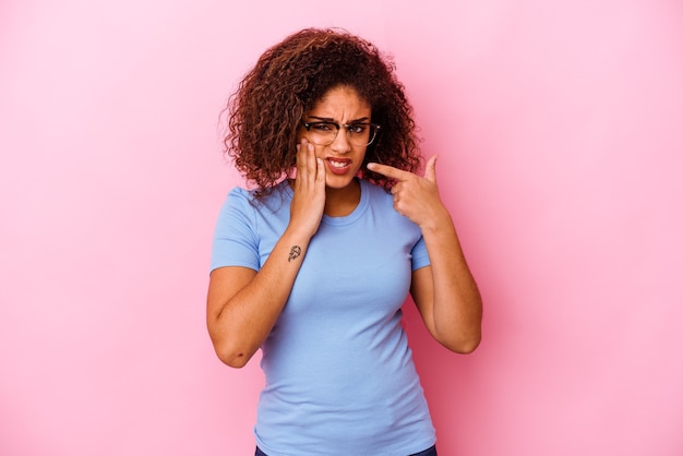 Giovane donna afroamericana isolata su sfondo rosa con un forte dolore ai denti, dolore molare.