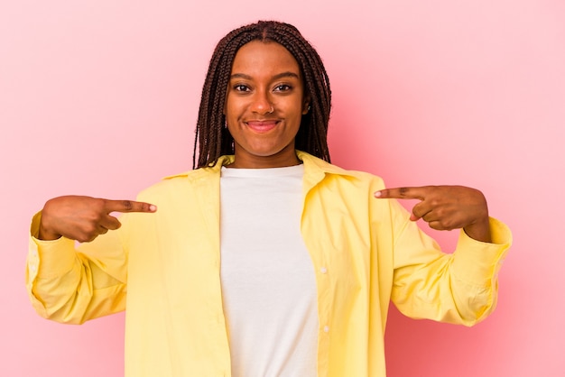 Giovane donna afroamericana isolata su sfondo rosa persona che indica a mano uno spazio copia camicia, orgogliosa e fiduciosa