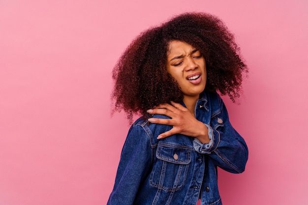 Giovane donna afroamericana isolata sul colore rosa che ha un dolore alla spalla.