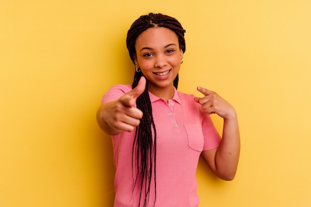 Giovane donna afroamericana isolata sulla parete gialla che punta alla parte anteriore con le dita.