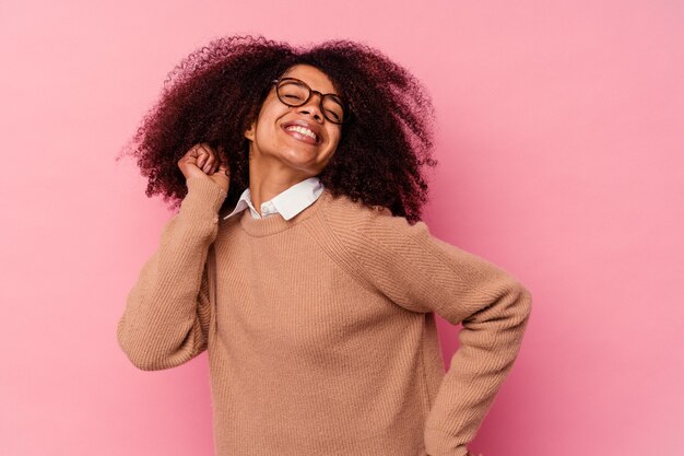 Giovane donna afroamericana isolata sulla parete rosa ballando e divertendosi.