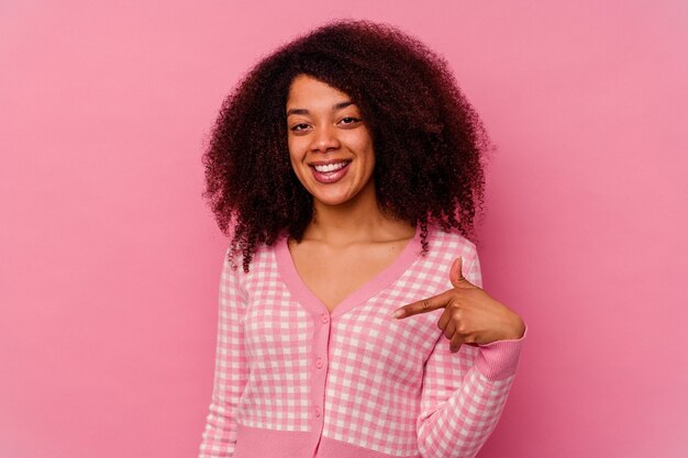 Giovane donna afroamericana isolata sulla persona rosa che indica a mano uno spazio della copia della camicia, orgoglioso e fiducioso