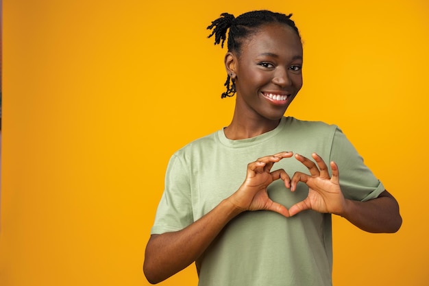 Giovane donna afroamericana sorridente e mostrando una forma di cuore con le mani