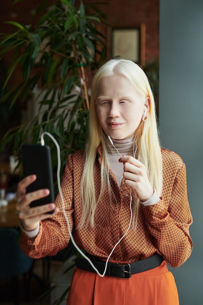 Giovane donna albina in camicetta intelligente che parla con un amico in video chat