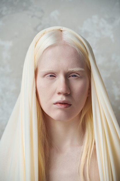 Giovane donna albina serena con copertina bianca sulla testa