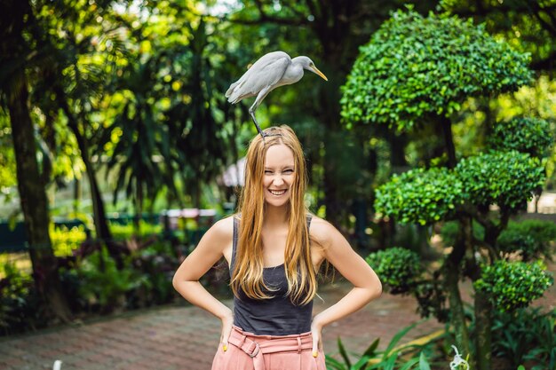 Giovane donna alimentazione ibes nel parco Garzetta Airone guardabuoi Bubulcus ibis Waters Edge acconciatura viziata