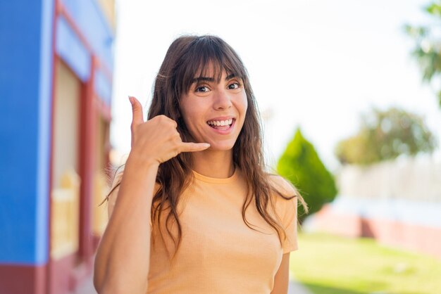 Giovane donna all'aperto che fa il gesto del telefono Call me back sign