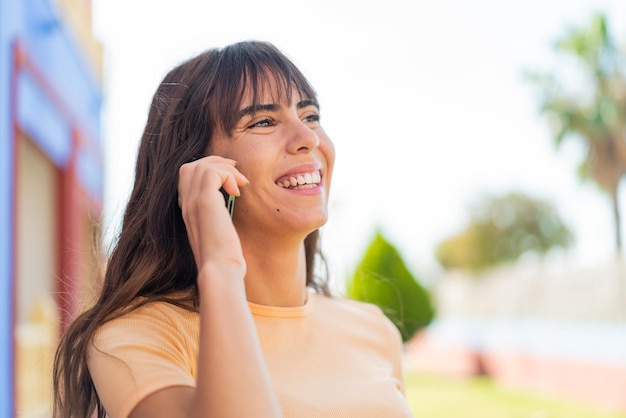 Giovane donna all'aperto mantenendo una conversazione con il telefono cellulare