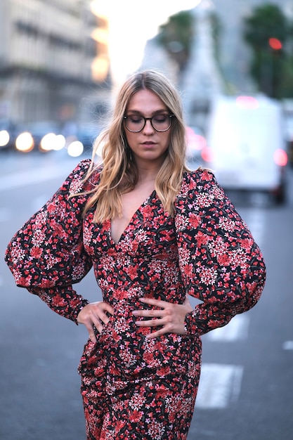 Giovane donna alla moda che guarda mentre posa per la telecamera in una strada di Barcellona