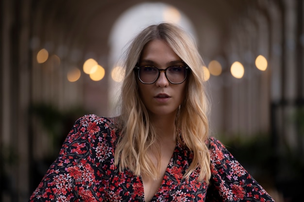 Giovane donna alla moda che guarda mentre posa per la telecamera in una strada di Barcellona