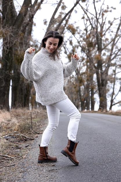 Giovane donna alla moda dalla strada asfaltata nella stagione fredda