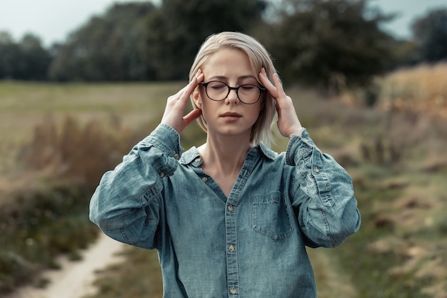 Giovane donna alla moda in camicia blu sulla strada della campagna