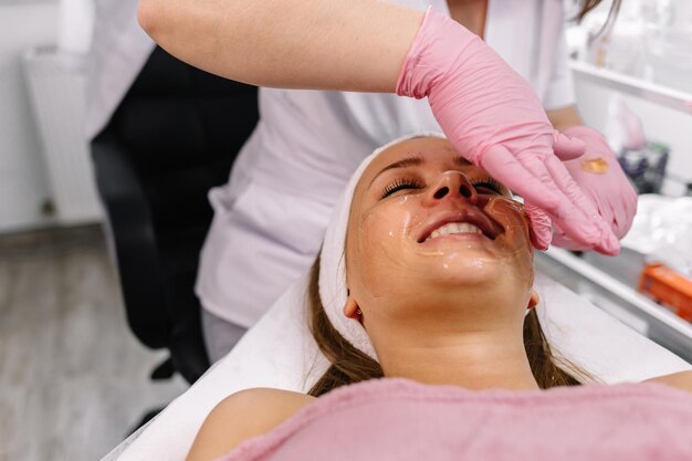 Giovane donna alle procedure della stazione termale che applicano maschera