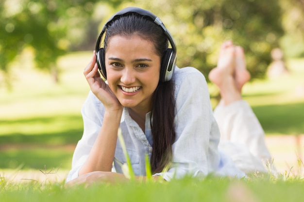 Giovane donna allegra che gode della musica in parco