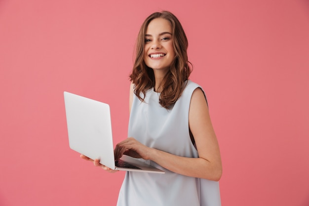 Giovane donna allegra che per mezzo del computer portatile.