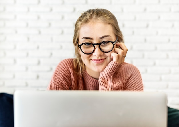 Giovane donna allegra che per mezzo del computer portatile