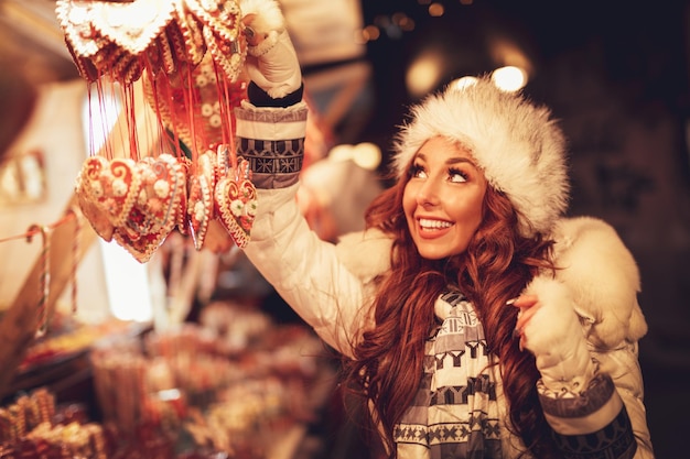 Giovane donna allegra che si diverte in un mercatino di Natale nella strada della città alla notte di Capodanno.