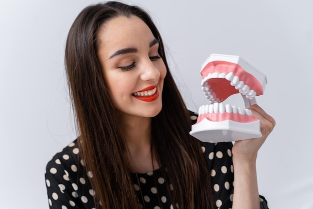 Giovane donna allegra con i denti di plastica. Denti bianchi e bel sorriso di bella donna.