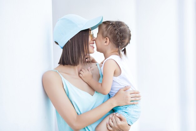 Giovane donna allegra con la sua piccola figlia all'aperto. Famiglia felice insieme in estate. Abbracciare mamma e bambino.