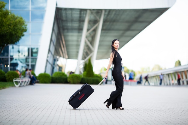 Giovane donna allegra con una valigia. Il concetto di viaggio e lavoro.
