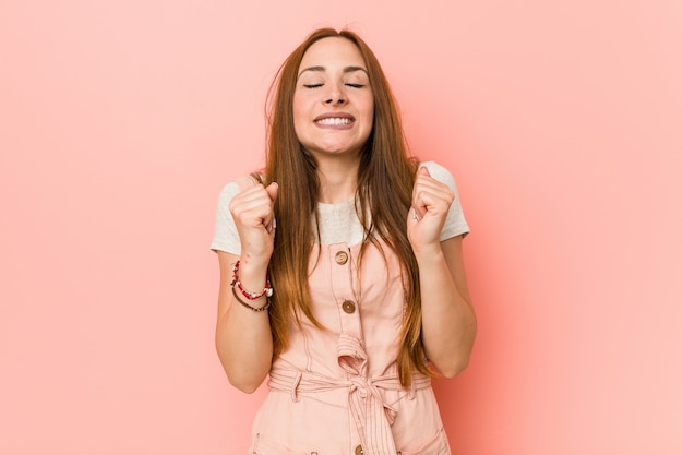 Giovane donna allo zenzero con lentiggini alzando il pugno, sentirsi felici e di successo. Concetto di vittoria.