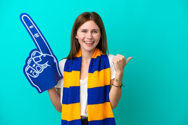 Giovane donna appassionata di sport isolata su sfondo blu che indica il lato per presentare un prodotto