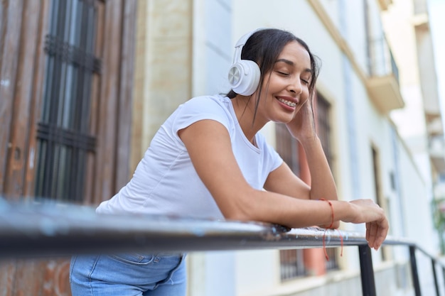 Giovane donna araba che ascolta musica appoggiata alla balaustra in strada