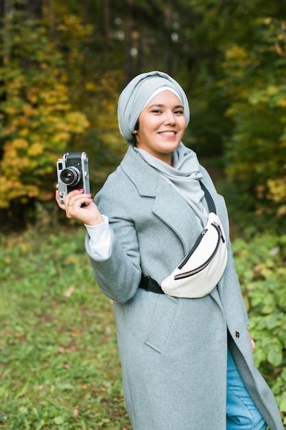 Giovane donna araba che indossa il velo hijab fotografare con uno smartphone nel parco ragazza musulmana moderna