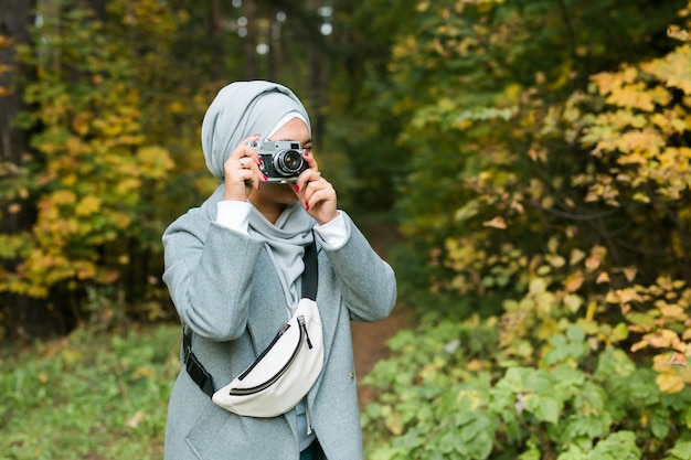 Giovane donna araba che indossa il velo hijab fotografare con uno smartphone nel parco ragazza musulmana moderna