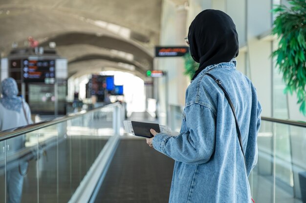 Giovane donna araba con il passaporto all'aeroporto pronta per una nuova avventura con l'aereo sullo sfondo
