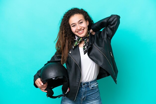 Giovane donna araba con un casco da motociclista isolato su sfondo blu ridendo