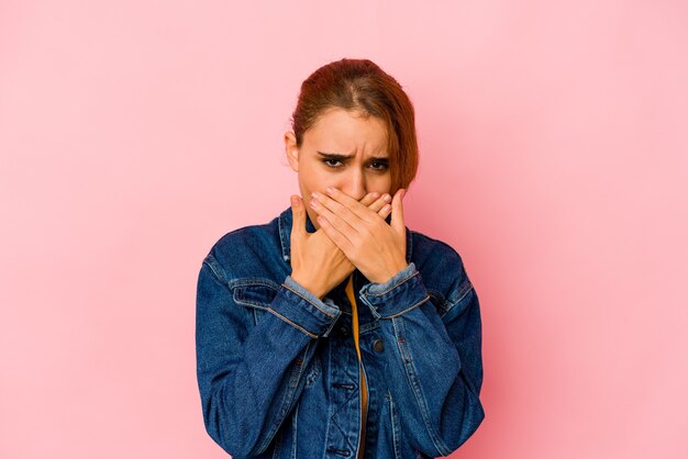 Giovane donna araba di razza mista che copre la bocca con le mani che sembrano preoccupate.