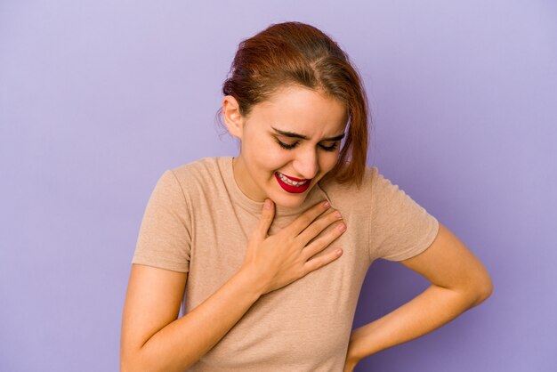 Giovane donna araba di razza mista che ride tenendo le mani sul cuore, il concetto di felicità.