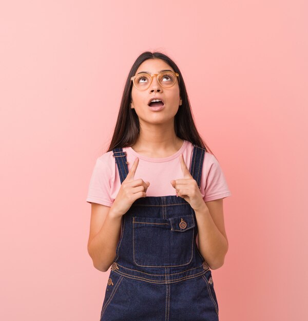 Giovane donna araba graziosa che indossa un denim dei jeans che indica parte superiore con la bocca aperta.