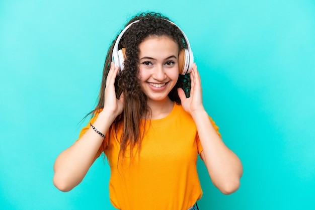 Giovane donna araba isolata su sfondo blu ascoltando musica