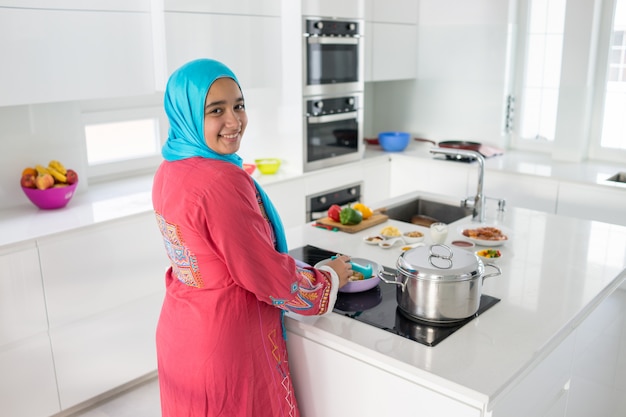 Giovane donna araba musulmana in cucina