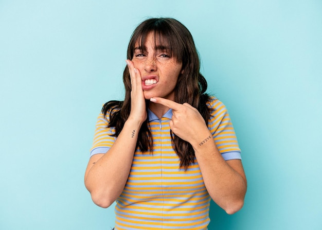 Giovane donna argentina isolata su sfondo blu con un forte dolore ai denti, dolore molare.