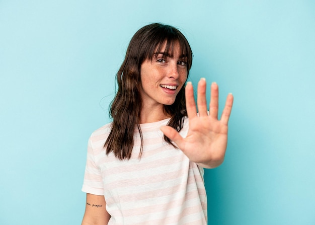 Giovane donna argentina isolata su sfondo blu sorridente allegra che mostra il numero cinque con le dita.