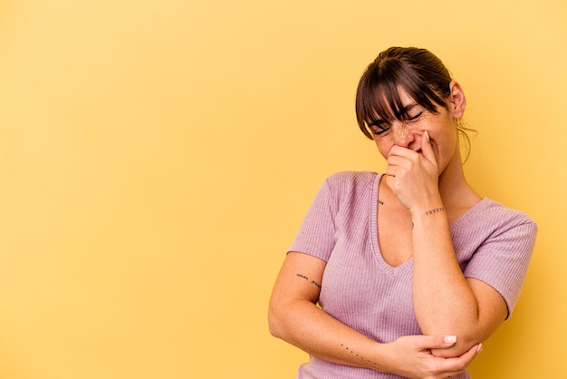 Giovane donna argentina isolata su sfondo giallo che ride felice, spensierata, emozione naturale.