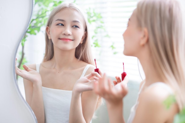 Giovane donna asiatica che applica il rossetto davanti allo specchio