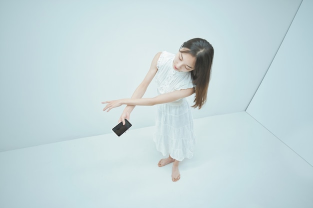 Giovane donna asiatica che balla mentre tiene in mano uno smartphone