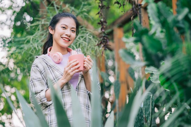 Giovane donna asiatica che beve il tè in giardino