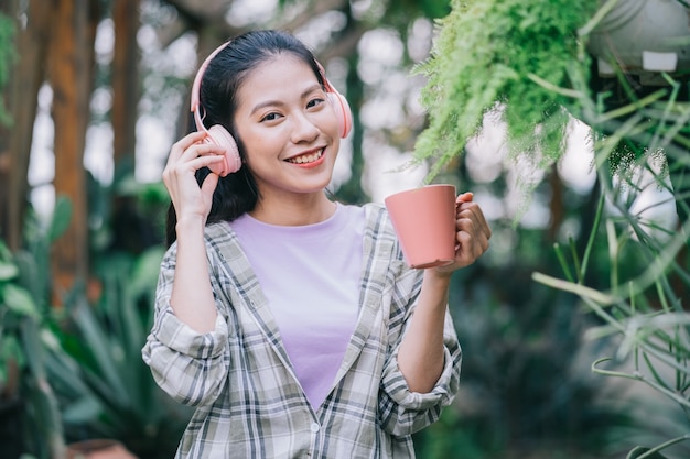 Giovane donna asiatica che beve il tè in giardino