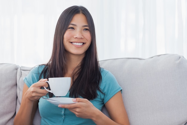 Giovane donna asiatica che beve tazza di tè