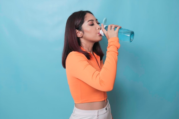 Giovane donna asiatica che beve una bottiglia d'acqua dopo l'esercizio di allenamento