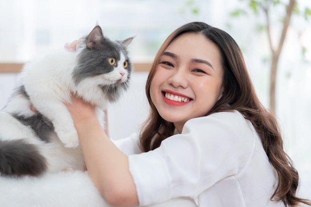 Giovane donna asiatica che gioca con il gatto a casa