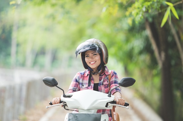 Giovane donna asiatica che guida una motocicletta in un parco