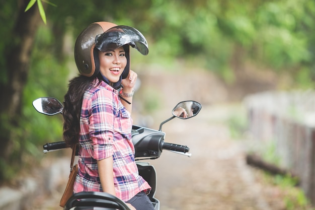 Giovane donna asiatica che guida una motocicletta in un parco