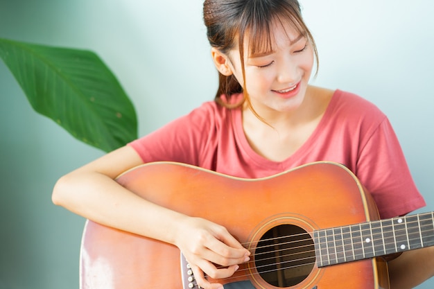 Giovane donna asiatica che impara chitarra a casa